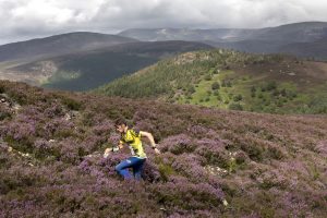 Running across the purple heather in the Scottish Highlands in an adventure sport